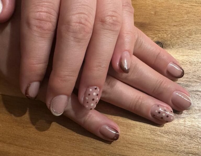 Kurze ovale Nude-Nägel mit schokoladenbrauner Micro-French, Glitzer-Akzenten und Konfetti-Punkten in Braun und Weiß